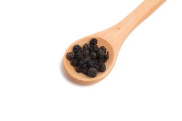 black dried pepper in wooden spoon isolated on the white
