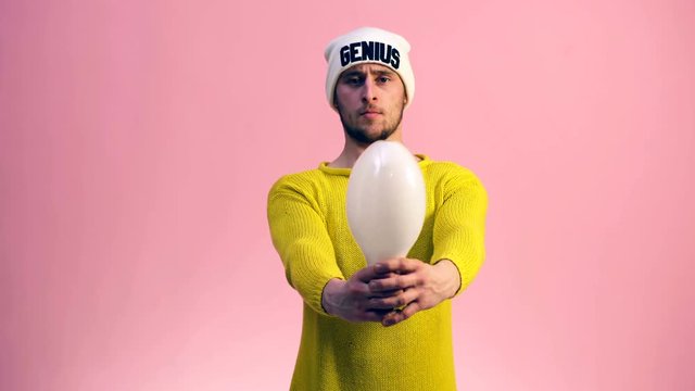The guy in a yellow sweater with a white hat on a pink background stretches a big lamp in his hands. Genius concept.