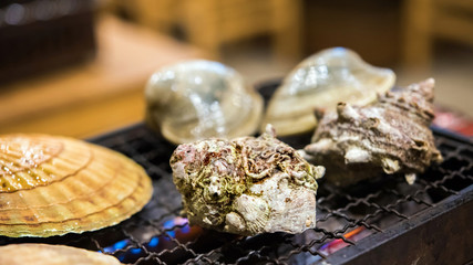 Mollusks are cooked in a cafe on fire, Tokyo, Japan. Close-up.