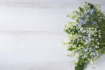 on a light table a bouquet of lilies of the valley and forget me nots