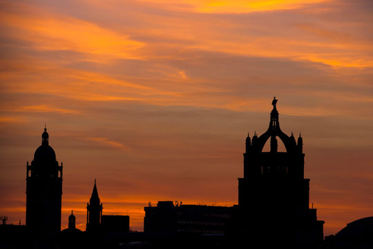 skyline di Londra al tramonto con colori arancio e nuvole grige