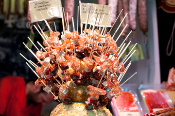 Assortment of Spanish meat sausages salchichon fuet chorizo on stick for sale at the Boqueria market in Barcelona