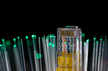 Yellow internet switch, green optical fibres close up macro shot on black background.