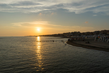 Fototapeta premium Children playing in the sea and enjoying sunset in Ostia Lido, Roma, Italy