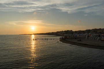 Children playing in the sea and enjoying sunset in Ostia Lido, Roma, Italy