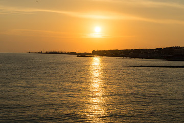Naklejka premium Children playing in the sea and enjoying sunset in Ostia Lido, Roma, Italy