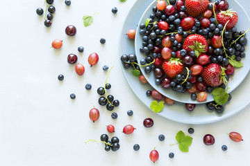 Fruit salad with strawberry, blueberry, cherry, gooseberry and black currant on wooden gray background. Flat lay. Top view