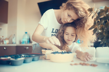 Obraz na płótnie Canvas mother and daughter prepare a pie / home mom and daughter in kitchen bake a blueberry pie, the concept of family home cosiness
