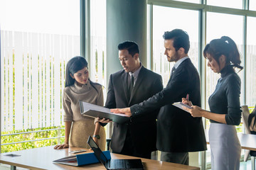 Executives and secretaries are discussing about the job information in a computer notebook.