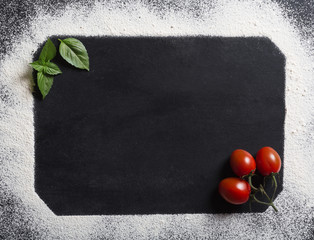 Baking background with copy space on black surface for your text. Top view. Tomatoes and basil on the table