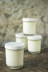 Four jars of homemade yogurt on a gray background. Dietary food