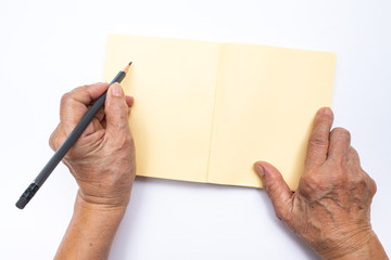 Senior woman's left hand with grey pencil writing on notebook isolated on white background,...