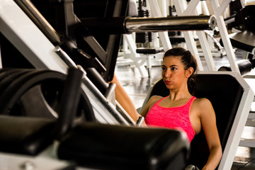 Plakat Attractive young woman exercising building muscles at the gym
