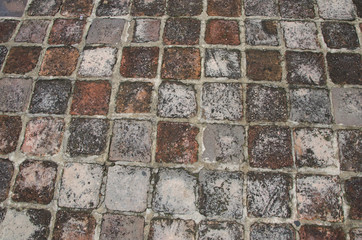 Old road pavement of the small rough granite tiles