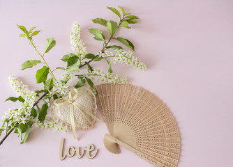 branch of white bird cherry, fan, words love and heart on a pink background