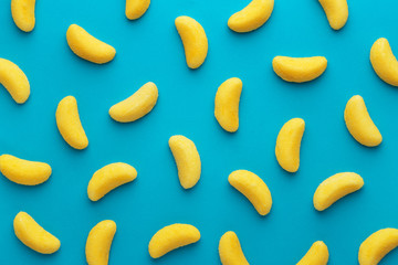 Banana shaped candy pattern on a blue background. Jelly candies viewed from above. Top view....