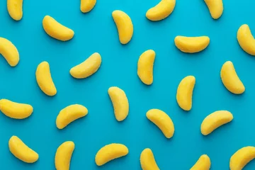 Poster Banana shaped candy pattern on a blue background. Jelly candies viewed from above. Top view. Repetition concept © virtustudio