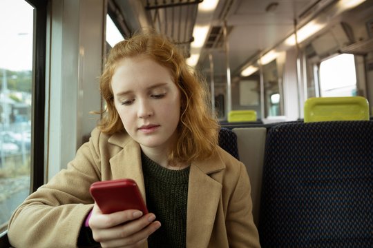 Woman using smartphone while traveling in train