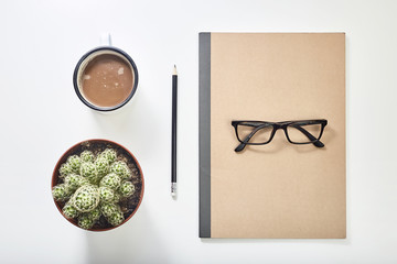 Desktop with vintage mug, glasses, notebook pen and plant