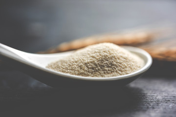 Raw unprepared semolina flour also known as Rava powder in Hindi in bowl or spoon. close-up...