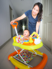 asian cute baby girl in the baby walker at home with mother