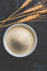 Raw unprepared semolina flour also known as Rava powder in Hindi in bowl or spoon. close-up isolated on white or moody background. selective focus