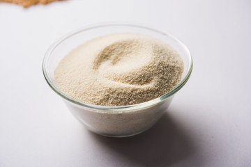 Raw unprepared semolina flour also known as Rava powder in Hindi in bowl or spoon. close-up isolated on white or moody background. selective focus