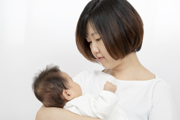 母に抱っこされ母と見つめ合う新生児の女の子