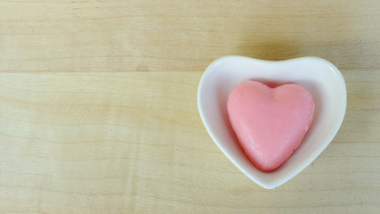 Heart soap in blow heart shaped on wooden table backgrounds above. Top views