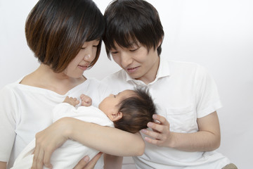 新生児を抱き見つめる若い夫婦、幸せな家族イメージ