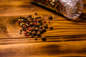 Pepper mill and scattered spices on the wooden table