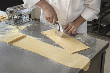 Cutting fresh Pasta Chef using a pizza cutter in preparation for an Italian plate