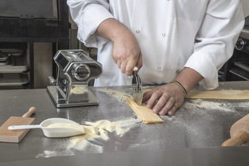 Cutting fresh Pasta Chef using a pizza cutter in preparation for an Italian plate