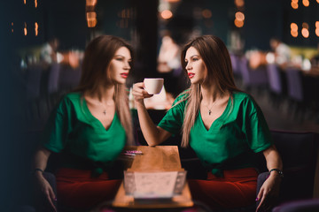 Emotional portrait of Fashion stylish sexy of  young hipster blonde woman, elegant lady, green top and red skirt, cool  girl. City view  urban dark cafe  lifestyle background.