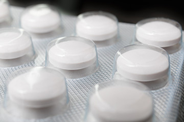 Round tablets on a black background in the package