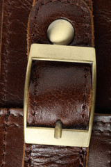 Belt with yellow metal clasp on a brown leather bag