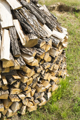 Wooden rectangular firewood for the stove and fire, stacked in a large pile on the outdoor.
