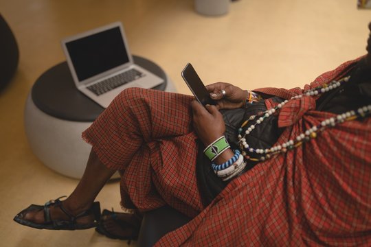 Maasai man in traditional clothing using mobile phone