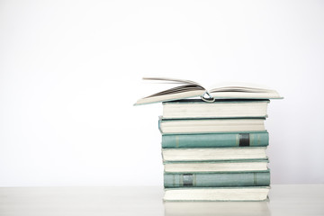 Open book resting on stack of books.white background