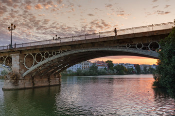Fototapeta na wymiar setting sun over the historic Puente de Triana bridge in Sevilla, Spain