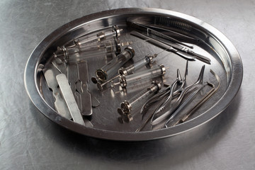 Syringes and various medical instruments on a metal tray