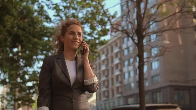 Elegant female communicates with her friend. Businesswoman wears trendy office outfit.