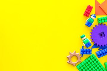 Developing children games mockup. Colorful plastic bricks and blocks on yellow background top view space for text