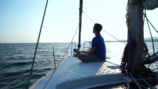 The guy on the yacht in the summer evening, Has a rest on the yacht, sits on a yacht nose