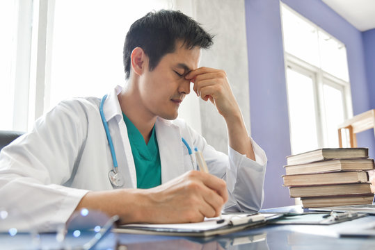 Stressed Young Asian male doctor is working.