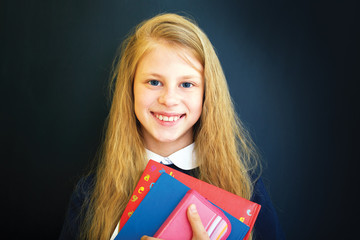 Happy little  school girl near school blackboard