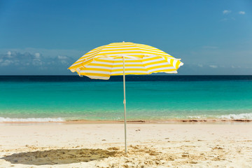 Yellow umbrella in the sun on pristine sandy Barbados beach