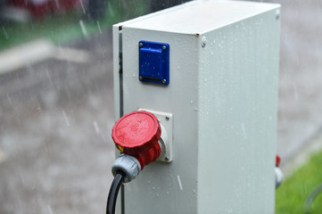 Raindrops are seen on industrial electric plug during heavy rain