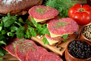 Sandwiches with salami, cheese and arugula salad surrounded by the ingredients