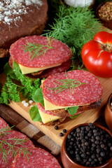 Sandwiches with salami, cheese and arugula salad surrounded by the ingredients